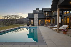 Modern exterior featuring dark vertical siding, a stone chimney, and a multi-level patio