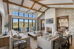 Spacious living area featuring exposed wood ceiling beams, a stone accent wall, and a central fireplace with a white mantel
