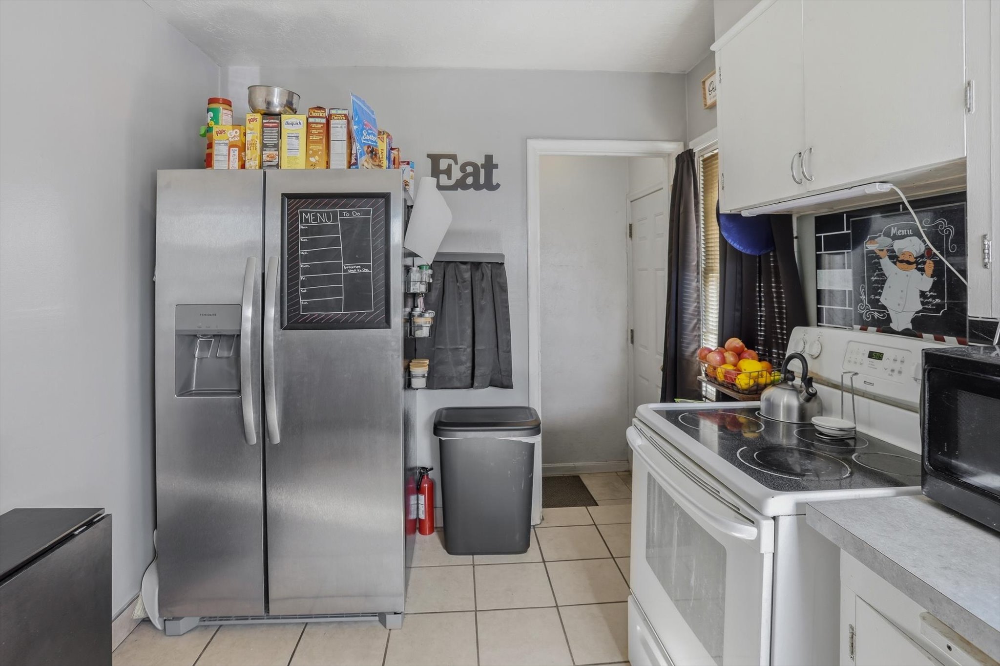 Kitchen featuring white cabinetry, light-toned countertops, tile flooring, and a white electric range