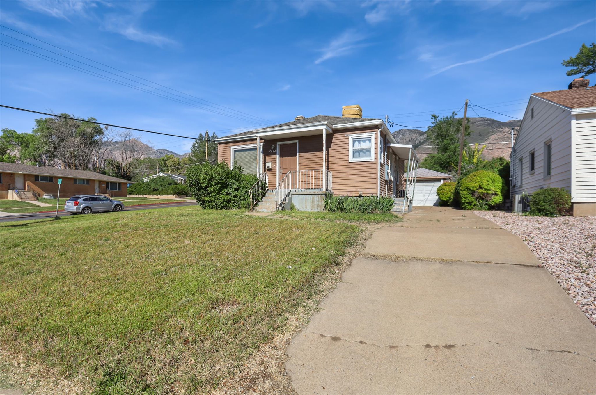 Brown siding exterior with a concrete driveway and detached garage