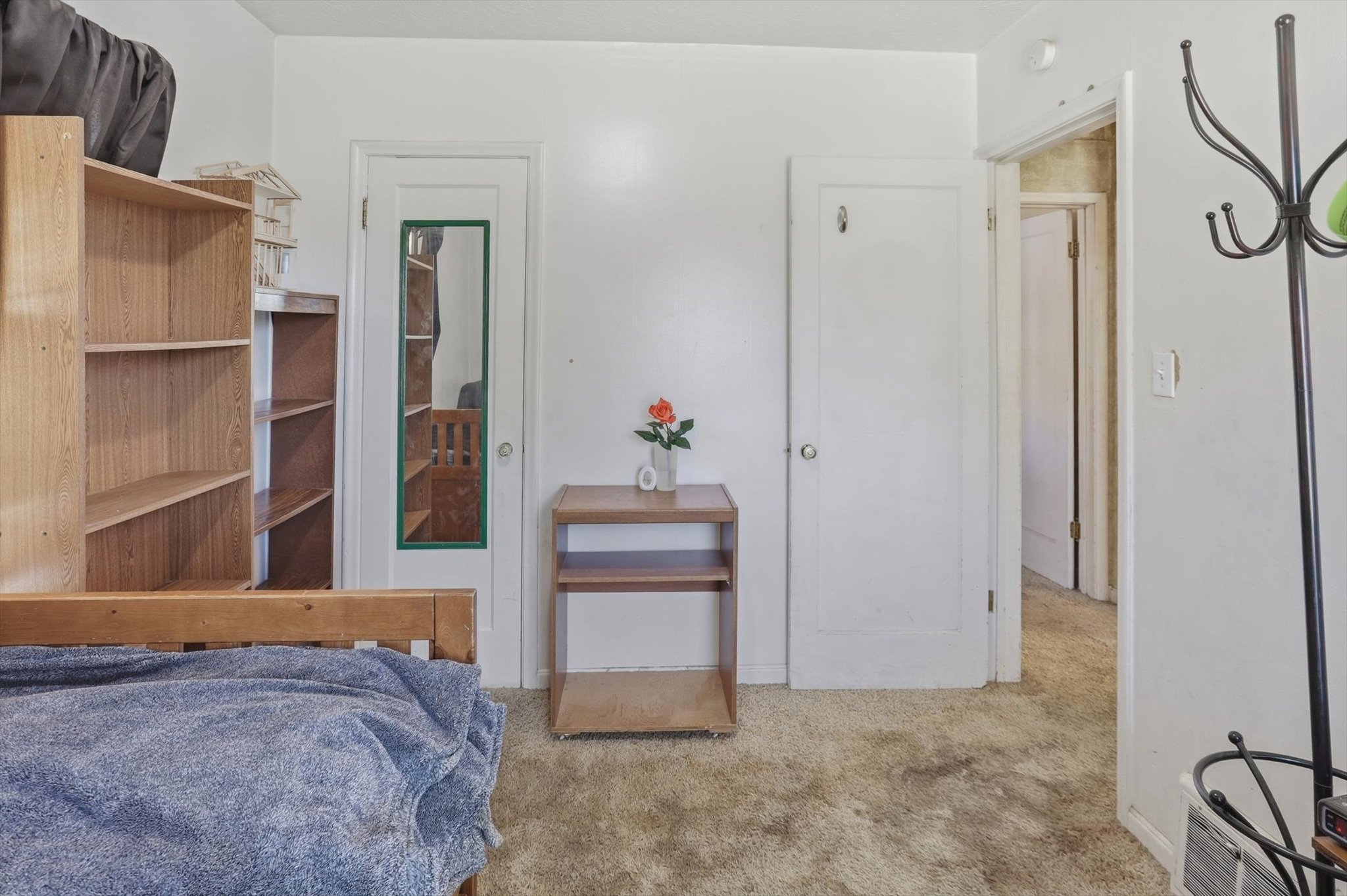 Neutral color palette throughout featuring a full-length mirror on one door, a second closed door, and a third open doorway revealing an interior space