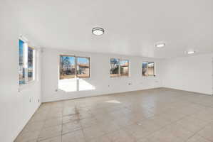 Spacious room featuring tile flooring, multiple windows, and recessed lighting fixtures