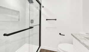 Contemporary bathroom featuring a frameless glass shower enclosure with matte black hardware, a recessed shower niche, light-toned wall tiling, and a vanity with a stone countertop