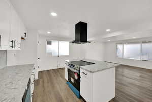 Open-concept kitchen featuring an island range with an overhead vent hood