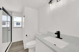 Modern bathroom featuring a single vanity with a light speckled countertop, matte black faucet, and under-mount sink