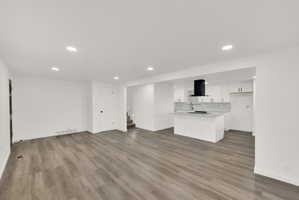 Open-concept interior featuring wood-finish flooring, recessed lighting, and white walls