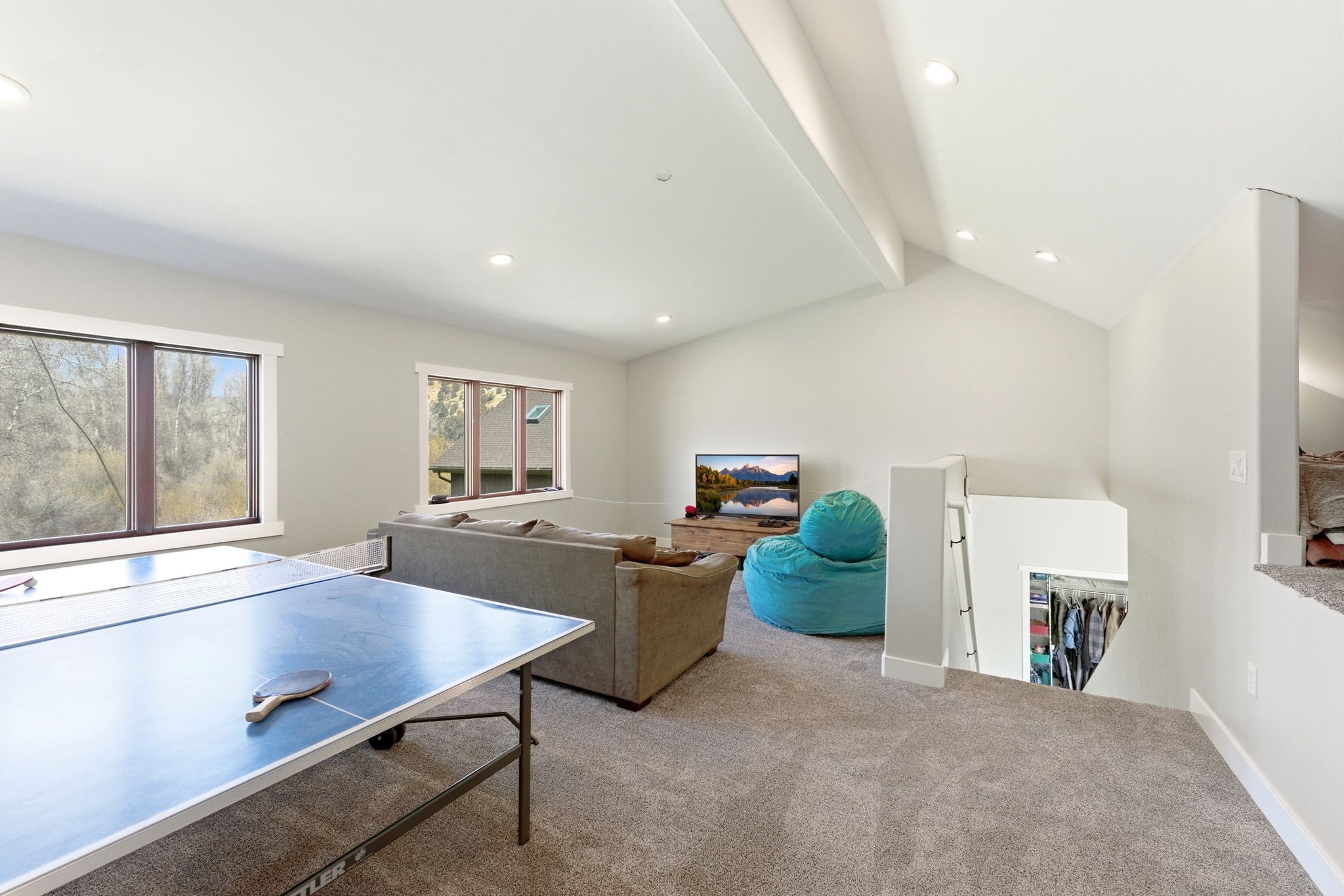 Carpeted bonus room featuring an open vaulted ceiling with exposed beams, recessed lighting, and multiple windows