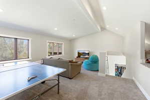 Carpeted bonus room featuring an open vaulted ceiling with exposed beams, recessed lighting, and multiple windows