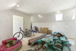 Unfinished room featuring sloped ceilings, recessed lighting, and dual skylights