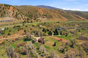 Expansive acreage featuring multiple structures, mature trees, open fields, and mountain terrain