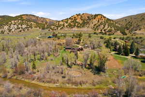 Expansive rural landscape featuring a winding river, verdant fields, and multiple structures set against rolling hills