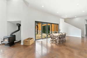 Open-concept living space featuring vaulted ceilings, a built-in wood-burning stove, stained concrete flooring, and a sliding glass door system