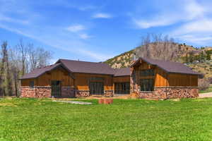 Wood siding and stone accents adorn this property, featuring a large grassy area