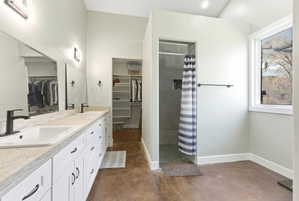 Bathroom featuring a dual vanity with white cabinetry and dark hardware