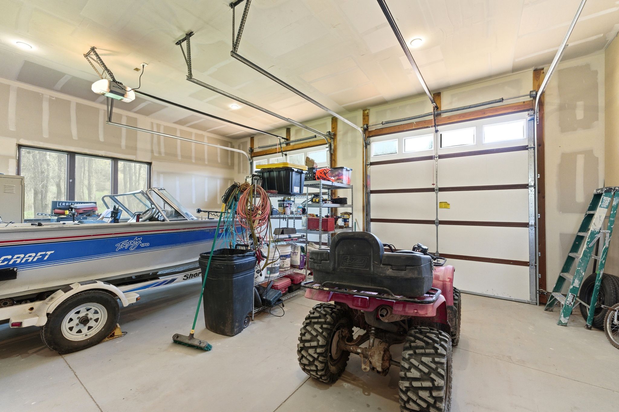 Spacious garage with multiple overhead doors, high ceilings, and recessed lighting