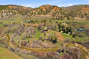 Expansive property featuring a meandering river, multiple residential structures, mature trees, and a mountainous backdrop