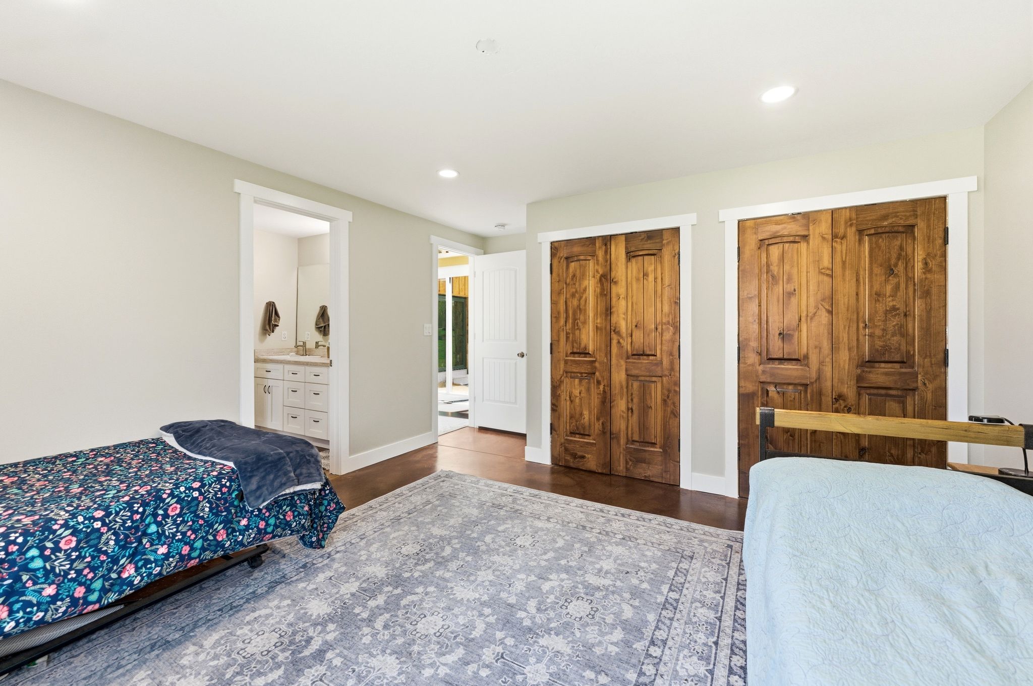 Spacious room featuring two sets of wood-panel bi-fold doors, recessed lighting, and rich wood-finish flooring