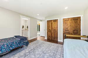 Spacious room featuring two sets of wood-panel bi-fold doors, recessed lighting, and rich wood-finish flooring