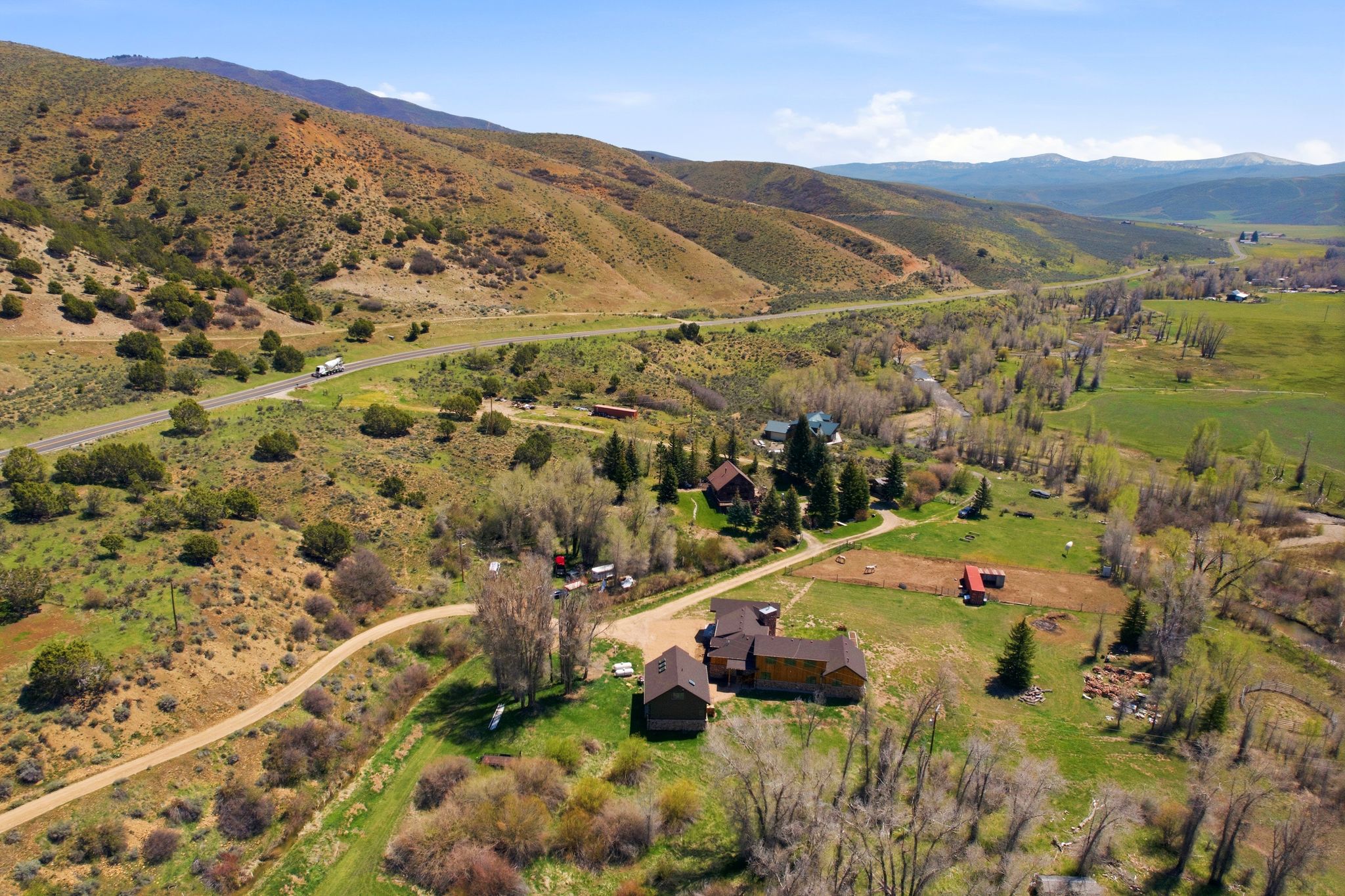 Rural property featuring multiple structures, extensive surrounding acreage, and a winding dirt road