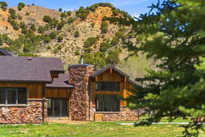 Stone and wood-sided exterior featuring multiple windows and a prominent stone chimney