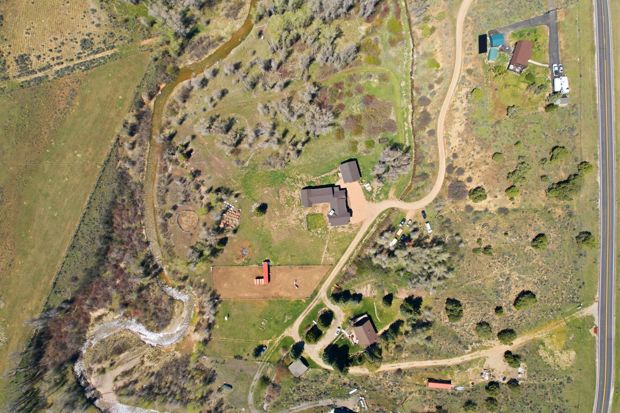 Expansive property featuring a main residence, secondary buildings, and a winding creek