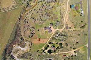 Expansive property featuring a main residence, secondary buildings, and a winding creek