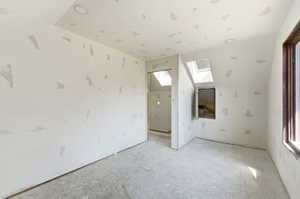 Unfinished interior space featuring a sloped ceiling with two skylights and recessed lighting