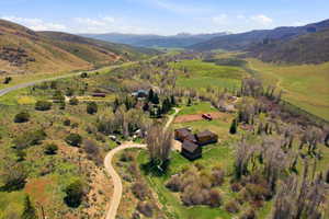 Expansive property featuring multiple structures, including a primary residence with multi-level roofing, situated within a verdant valley