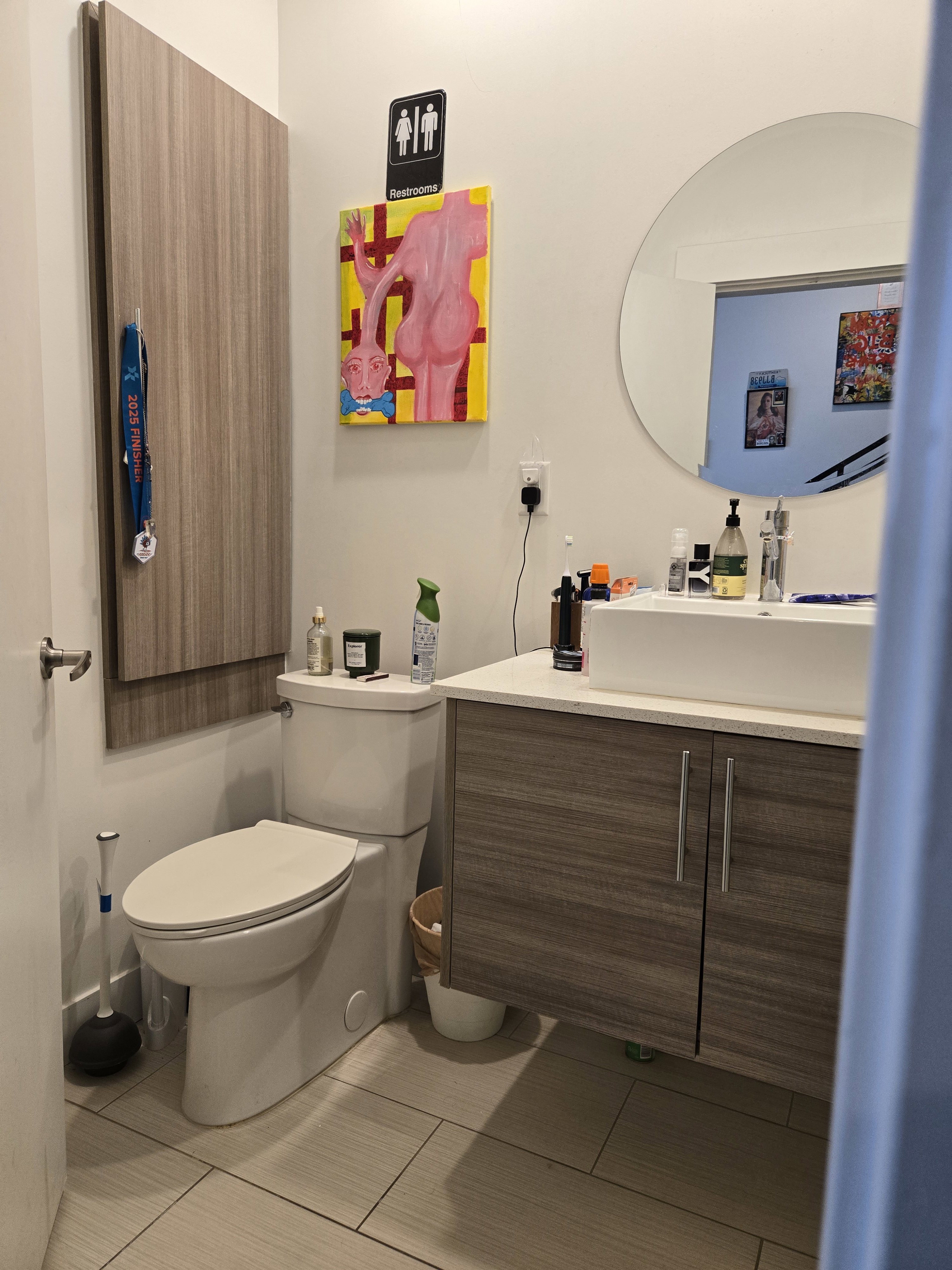 Modern bathroom featuring light-toned tile flooring and a white toilet