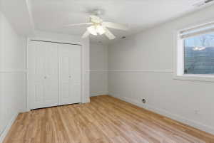 Room featuring wood-finish flooring, crisp white walls, and wainscoting
