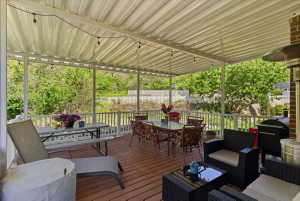 Expansive outdoor deck featuring a white metal patio cover, string lighting, and white railings