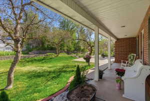 Expansive covered front porch featuring brick siding and concrete flooring