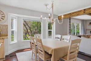 Dining area featuring a bay window, hardwood flooring, and a decorative wood beam