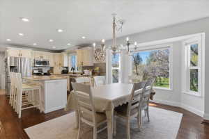 Open-concept kitchen and dining area featuring rich wood-finish flooring, recessed lighting, and a chandelier