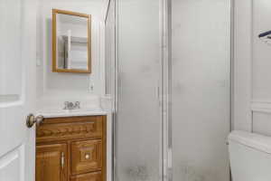 Bathroom with wood-finish vanity, integrated sink, chrome faucet, and framed mirror