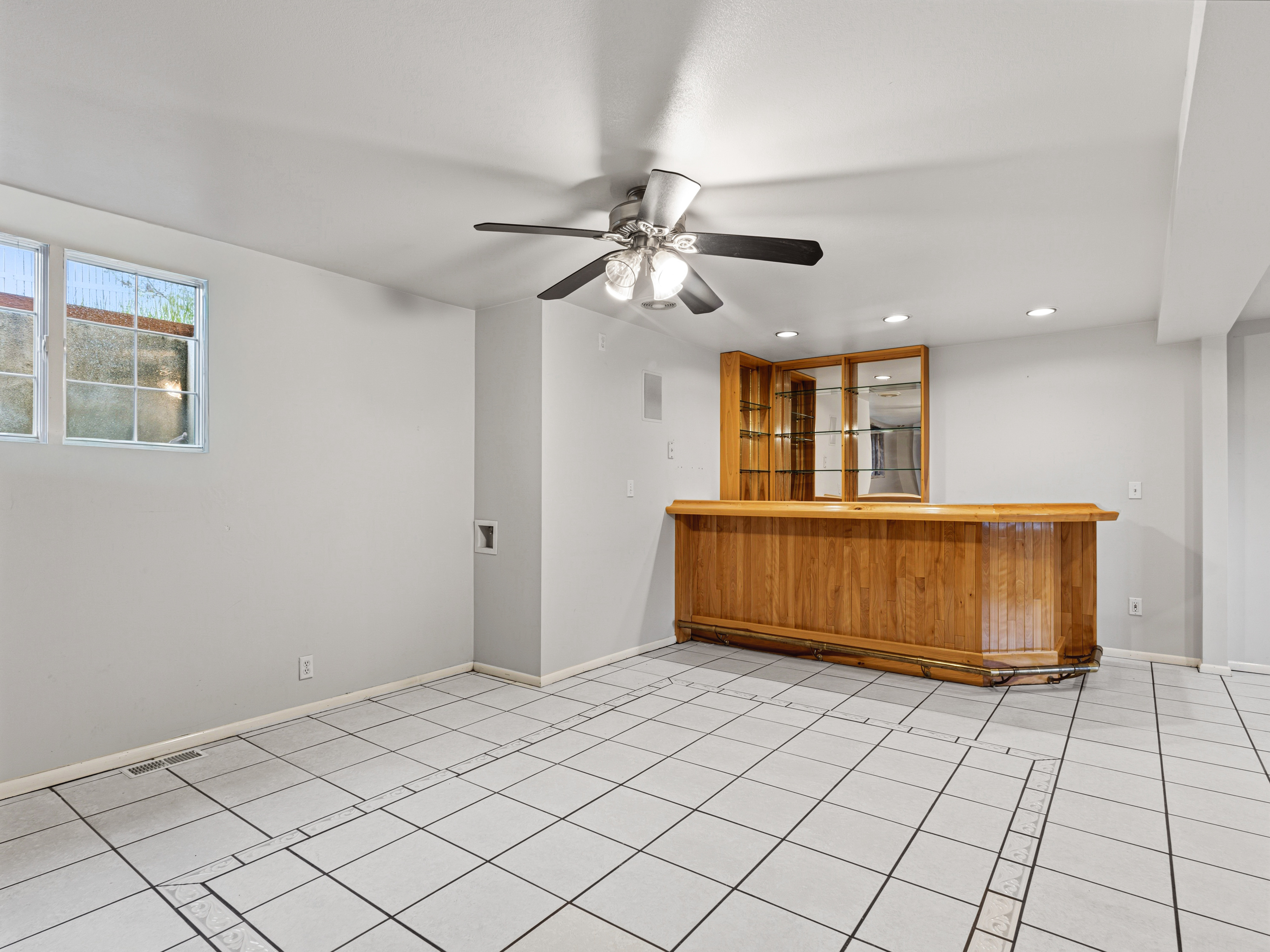 Spacious room featuring a built-in wood-finish wet bar with shelving, integrated lighting, and a mirrored backsplash