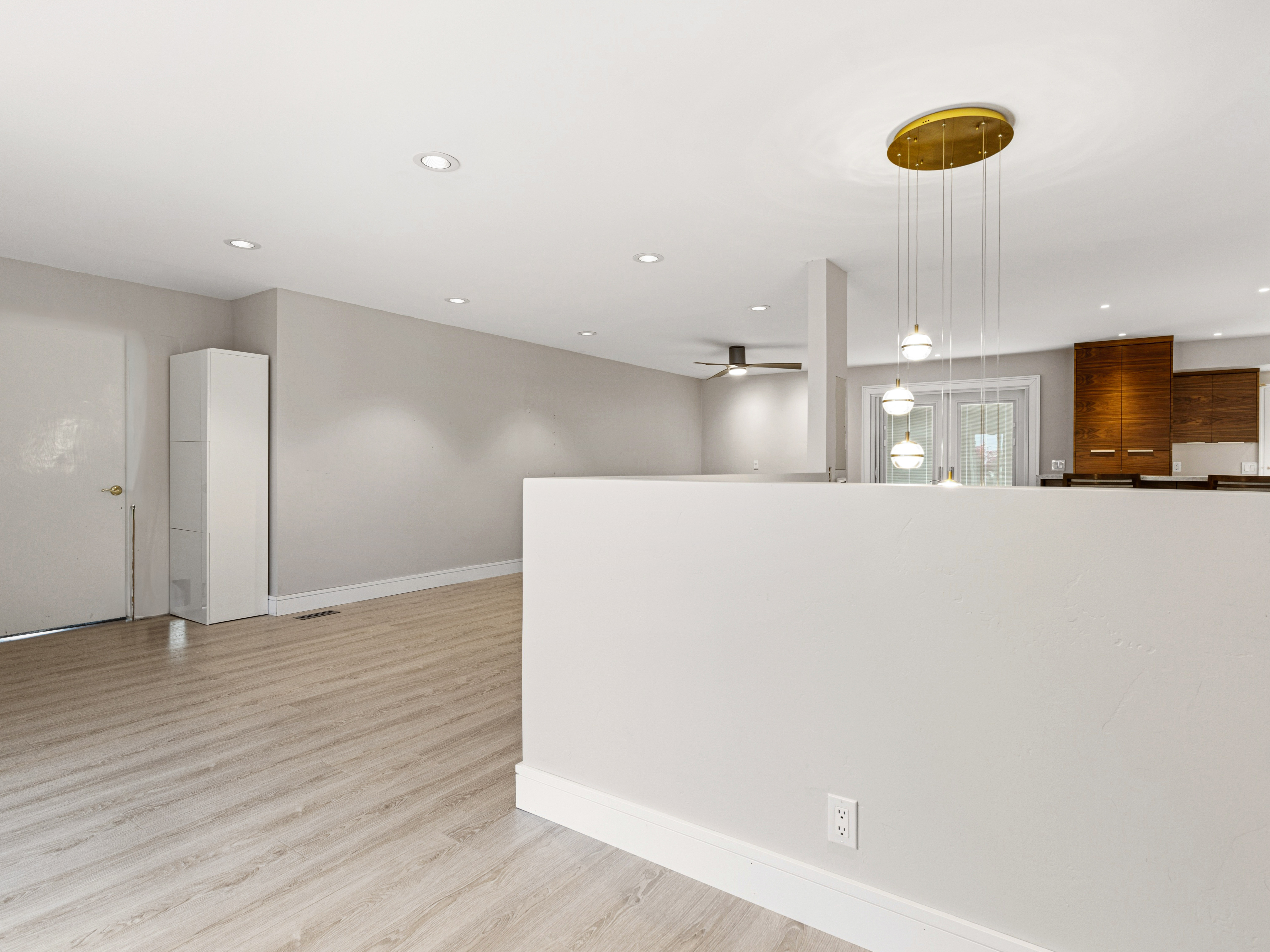 Open-concept living area with wood-finish flooring, recessed lighting, and a modern multi-pendant chandelier