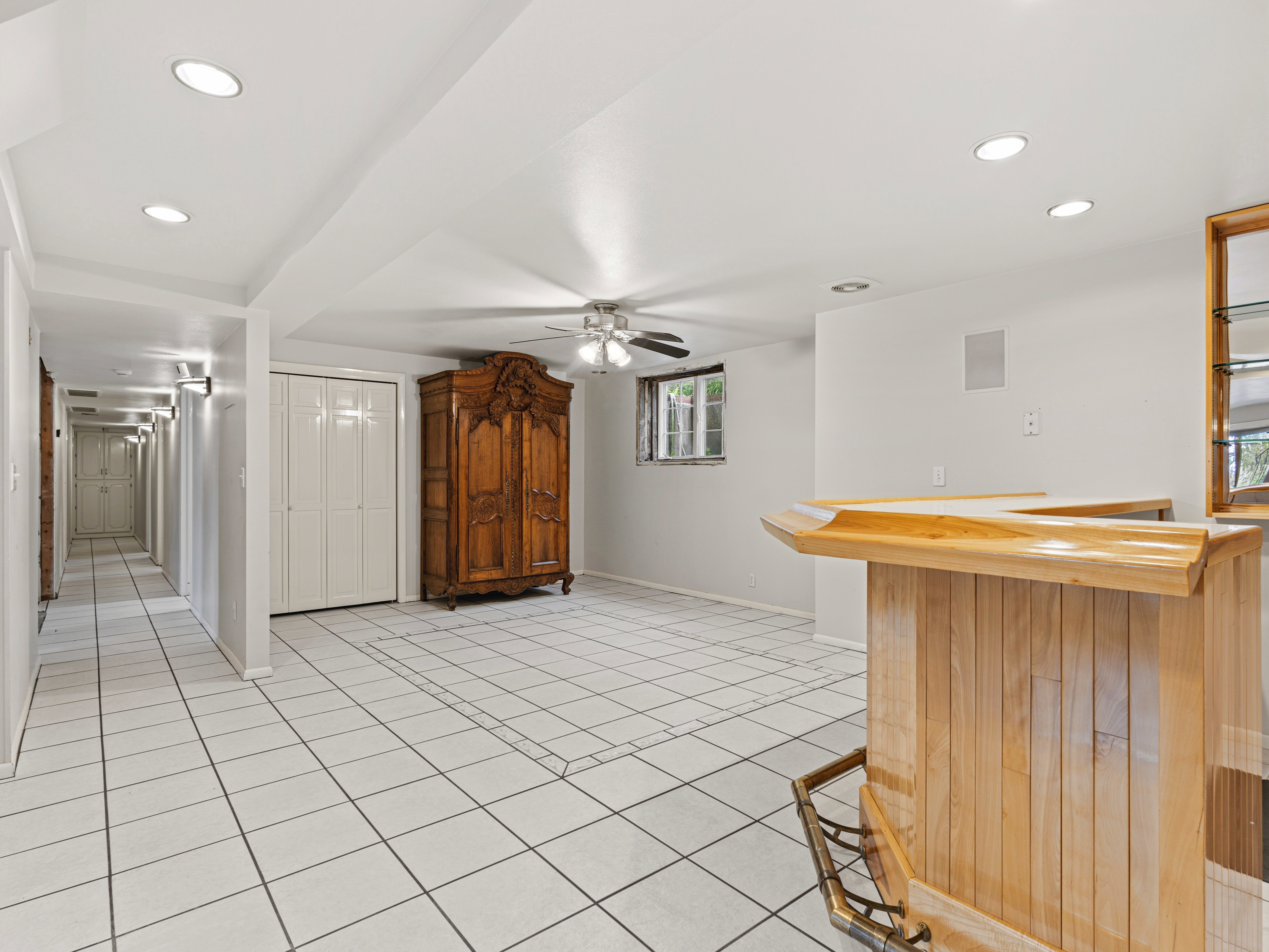 Spacious room featuring white tile flooring and a built-in wooden bar