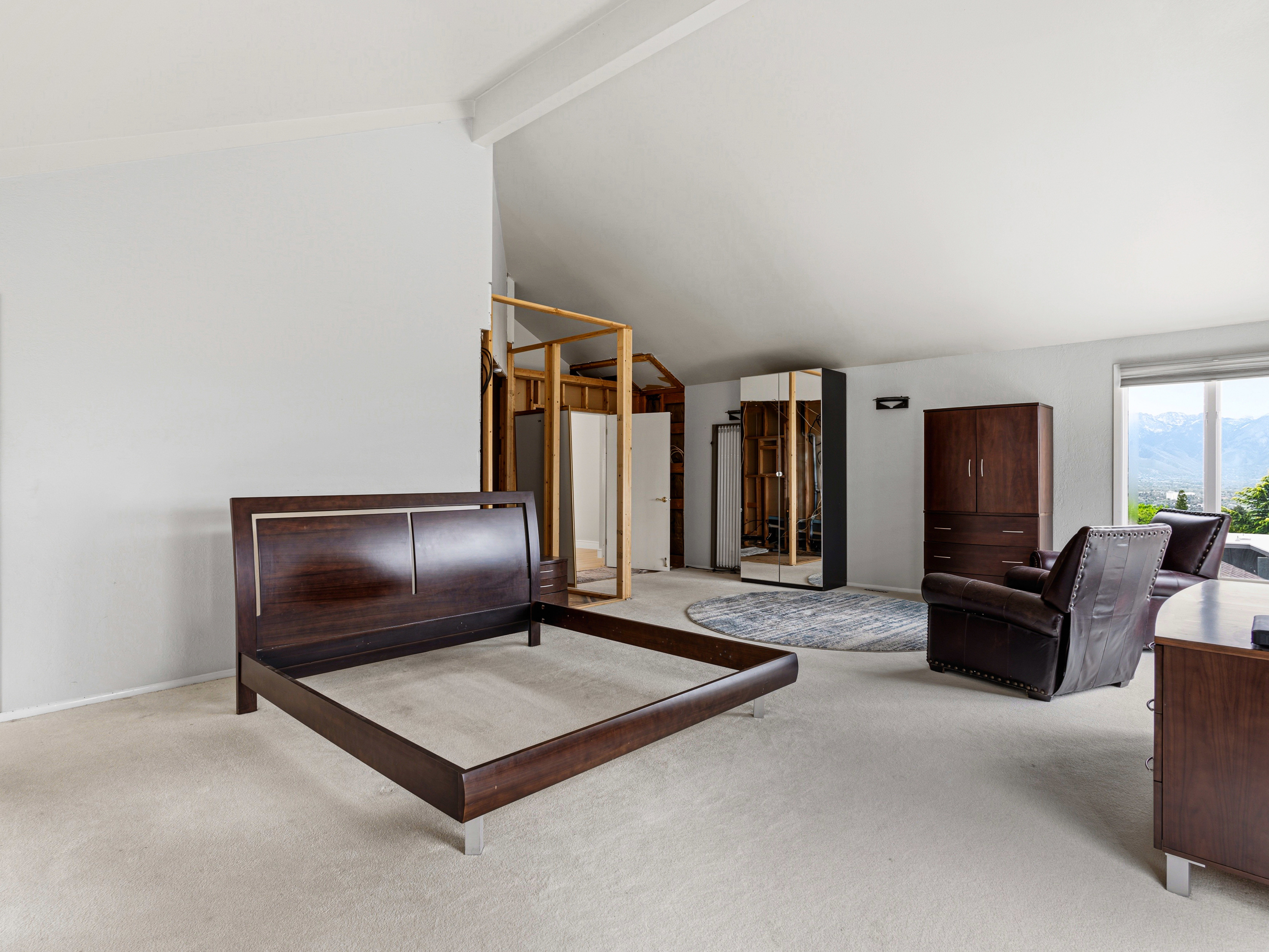 Spacious room featuring vaulted ceilings and light-toned carpeting