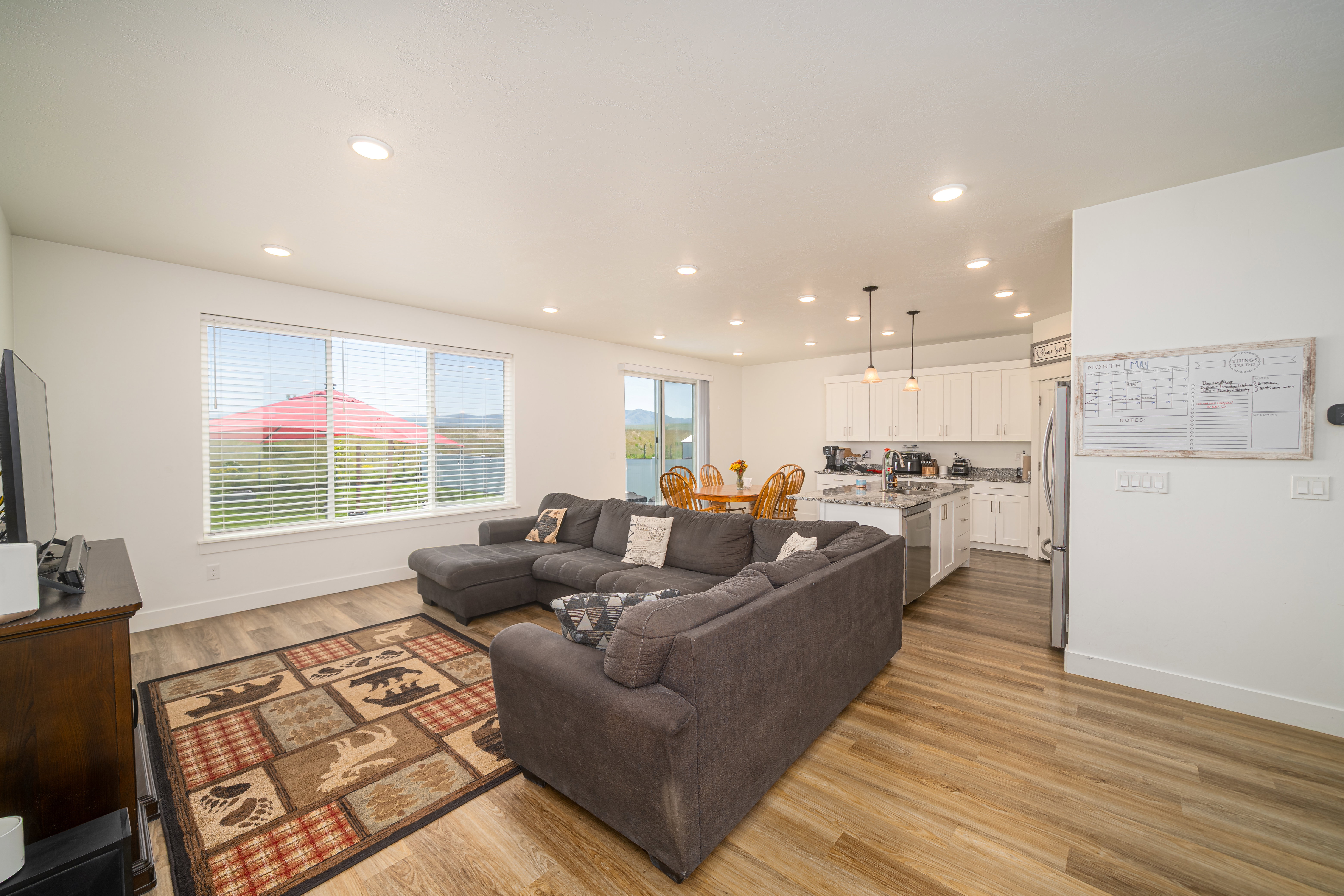 Open-concept living space featuring wood-finish flooring, recessed lighting, and a kitchen with white cabinetry and stainless steel appliances