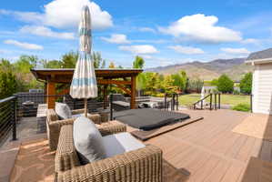 Multi-level outdoor deck featuring a hot tub, cable railing, and a covered pergola