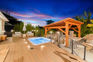 Expansive multi-level outdoor living space featuring a built-in spa, wood-finish decking, and a timber pergola