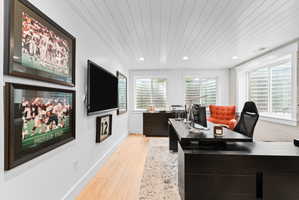 Recessed lighting illuminates a shiplap ceiling in this dedicated office space