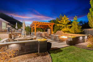 Terraced backyard oasis featuring a natural gas fire pit, integrated seating, and a dedicated pergola-covered outdoor kitchen