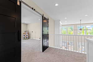 Carpeted loft area featuring a white baluster railing and multiple recessed light fixtures