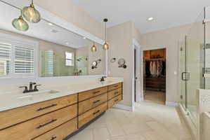 Dual vanity with wood-finish cabinetry, light-toned countertops, and matte black fixtures