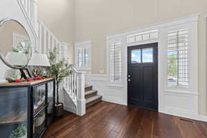 Entryway featuring wood-finish flooring, a dark-paneled door with glass inserts, and surrounding sidelight windows