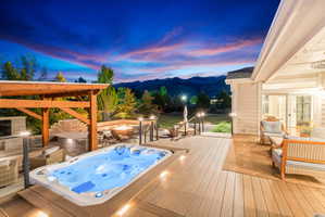 Backyard featuring a built-in spa, expansive composite decking, a wood pergola, and a stone fire pit area