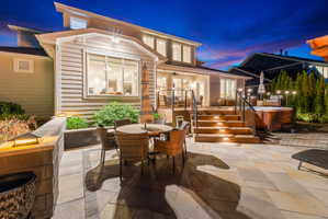 Expansive patio featuring stone pavers, a raised wood deck with integrated lighting, and a built-in spa