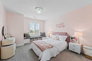 Bedroom featuring a window seat with storage, white plantation shutters, and a crystal flush mount light fixture